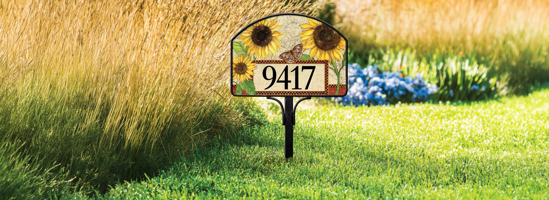 Sunflower yard sign in a sunlit autumn garden with ornamental grasses